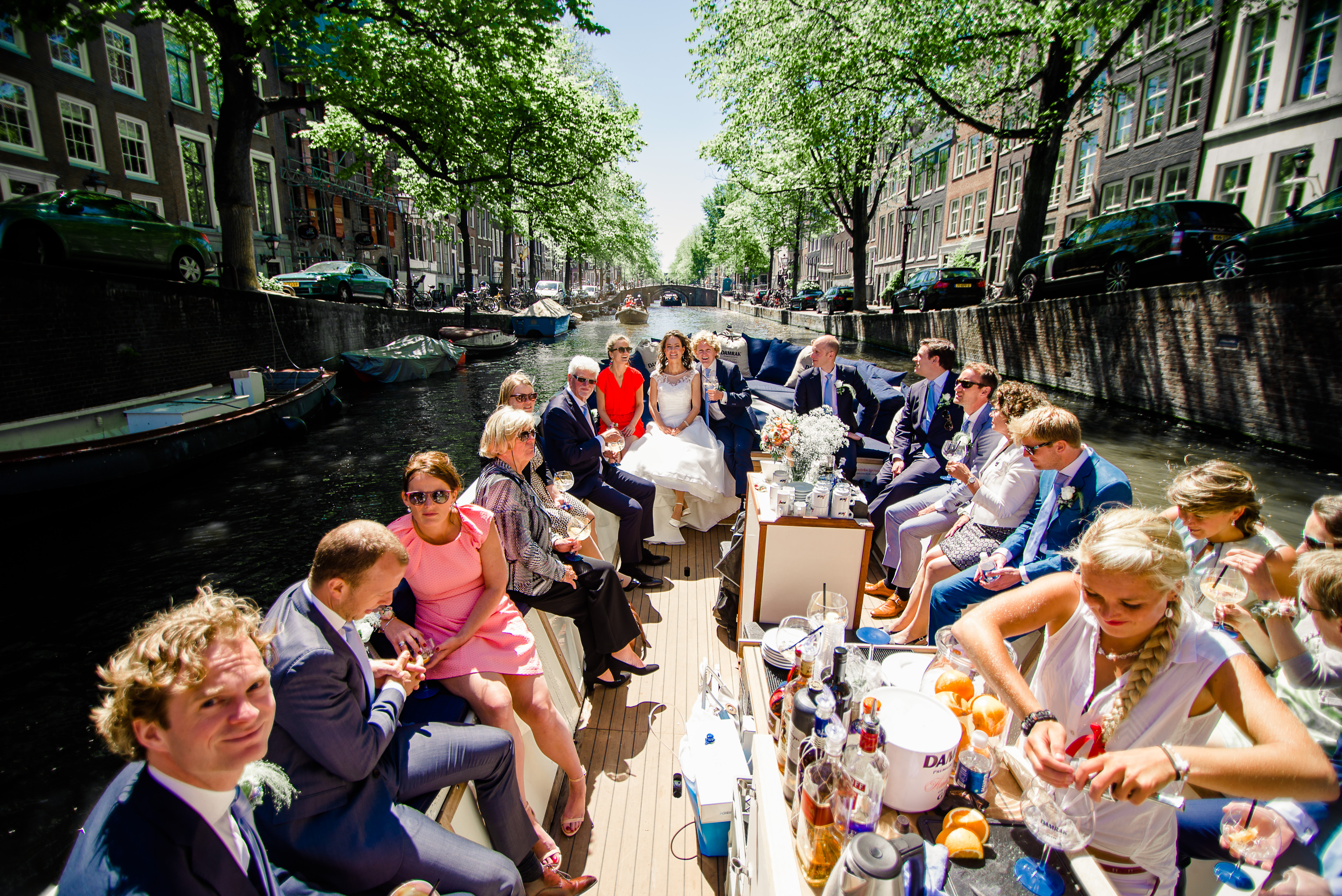 Bruidspaar en gasten varen in een salonboot door de Amsterdamse grachten