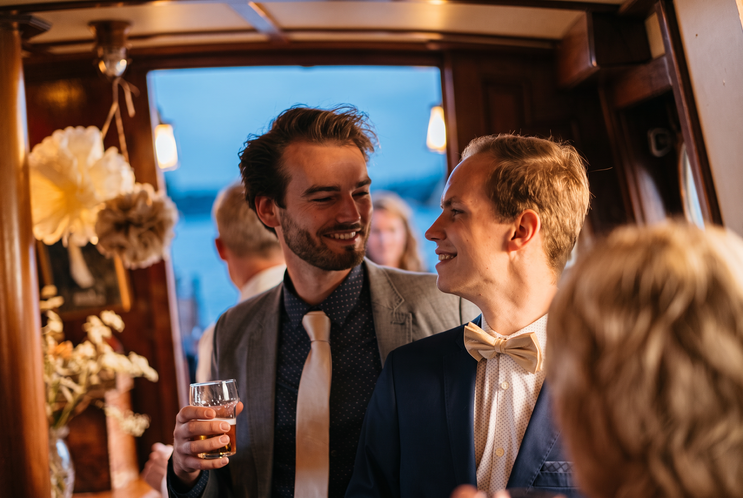 Gasten in gesprek in het warme lamplicht van de salon bij het vallen van de avond